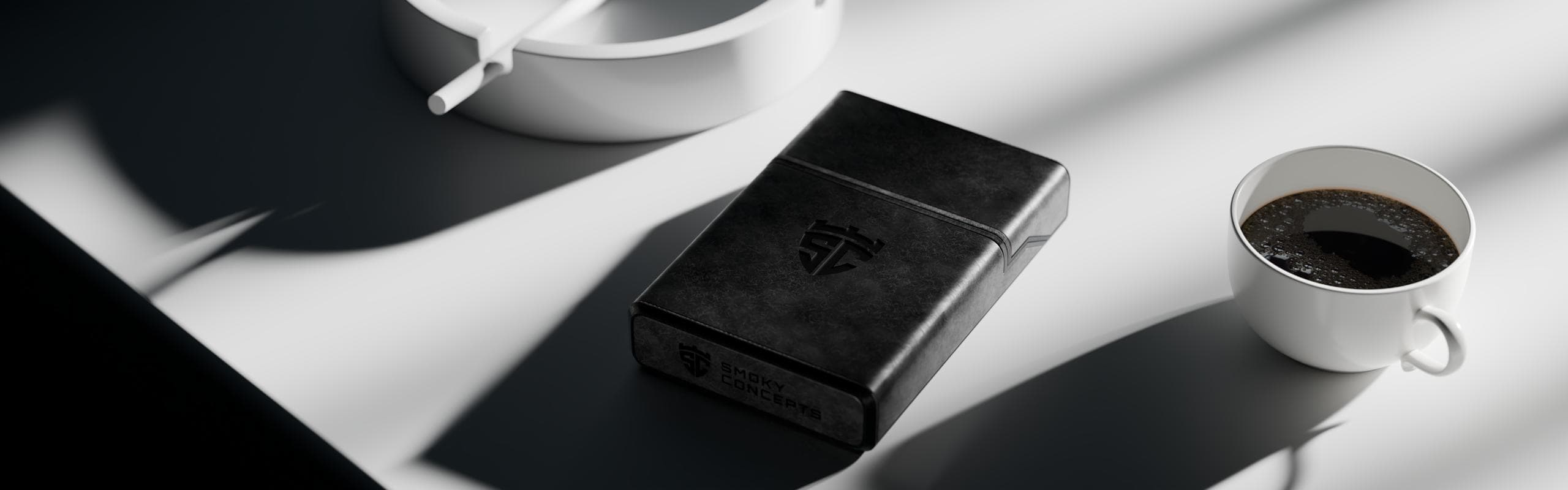 Black leather cigarette case on a table next to a cup of coffee